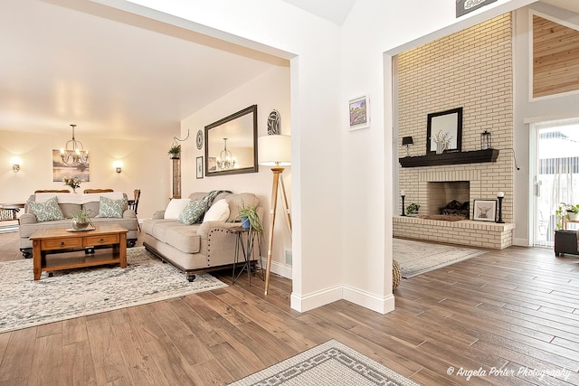 living room featuring an inviting chandelier, hardwood / wood-style floors, and a fireplace