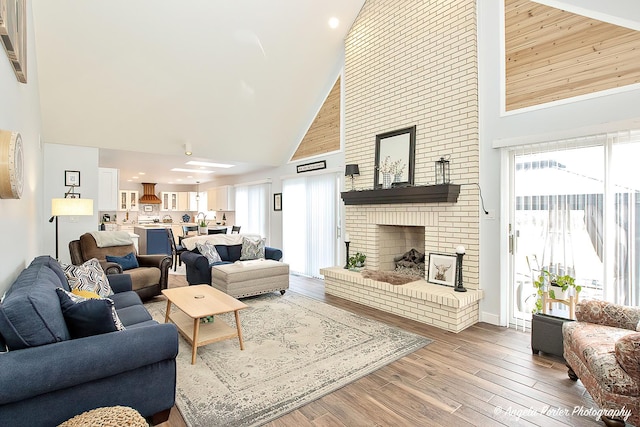 living room with wood-type flooring, plenty of natural light, a fireplace, and high vaulted ceiling