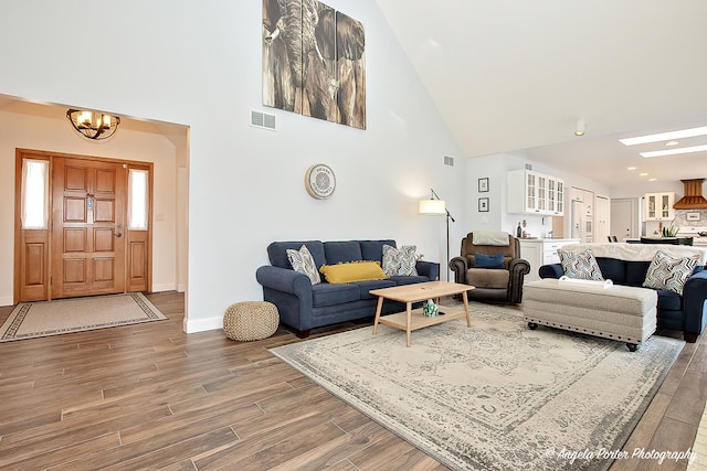 living room with hardwood / wood-style flooring, high vaulted ceiling, and a notable chandelier