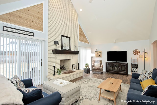 living room featuring a brick fireplace, hardwood / wood-style flooring, and high vaulted ceiling