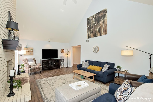 living room with a brick fireplace, hardwood / wood-style floors, and high vaulted ceiling