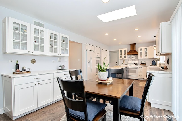 dining room with sink, a skylight, and light wood-type flooring