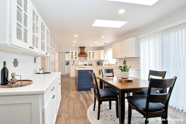 dining space with a skylight, light hardwood / wood-style flooring, and sink