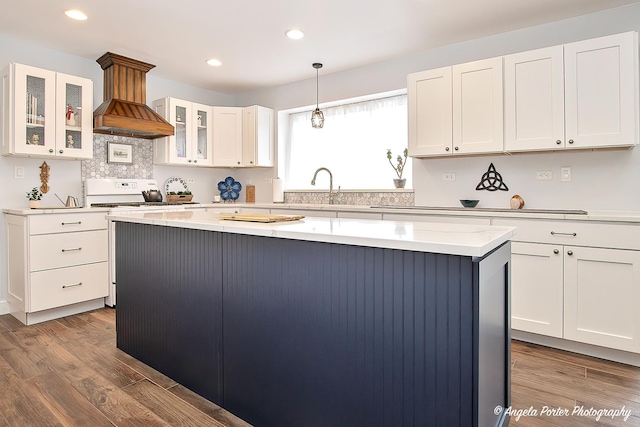 kitchen with white cabinetry, hanging light fixtures, a kitchen island, hardwood / wood-style flooring, and stove