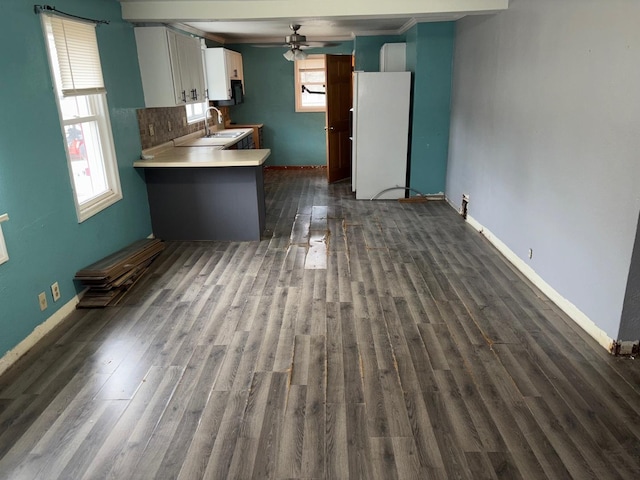 kitchen featuring sink, white cabinetry, white refrigerator, dark hardwood / wood-style flooring, and kitchen peninsula