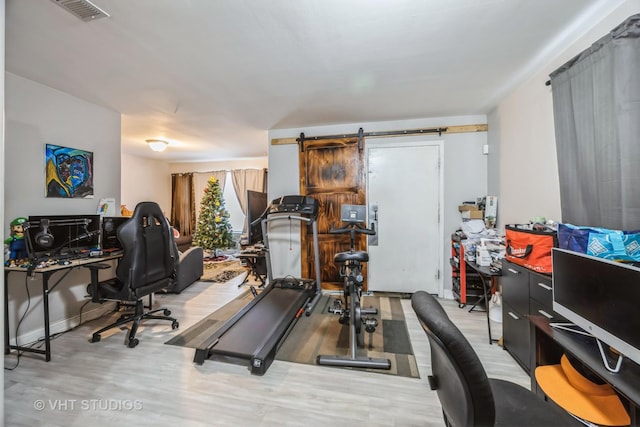 workout area featuring a barn door and light wood-type flooring