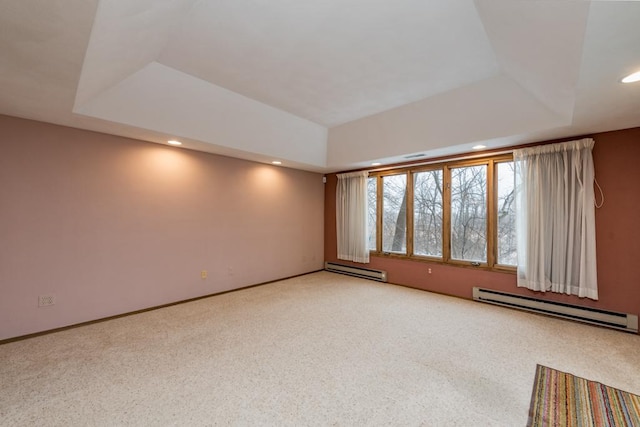 carpeted spare room featuring baseboard heating and a tray ceiling