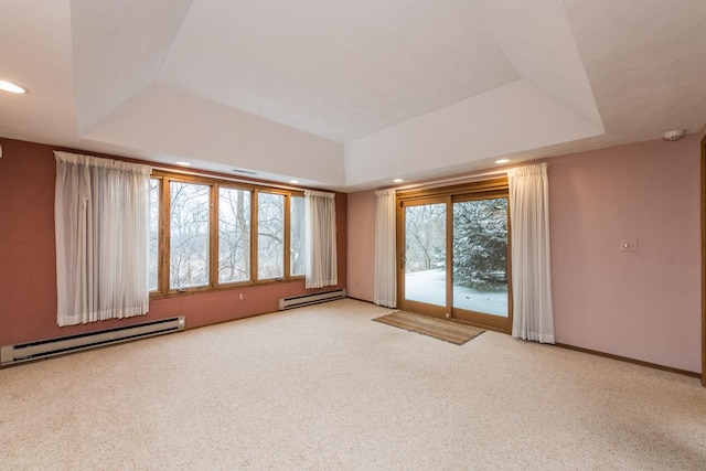 carpeted empty room with a raised ceiling, plenty of natural light, and a baseboard heating unit