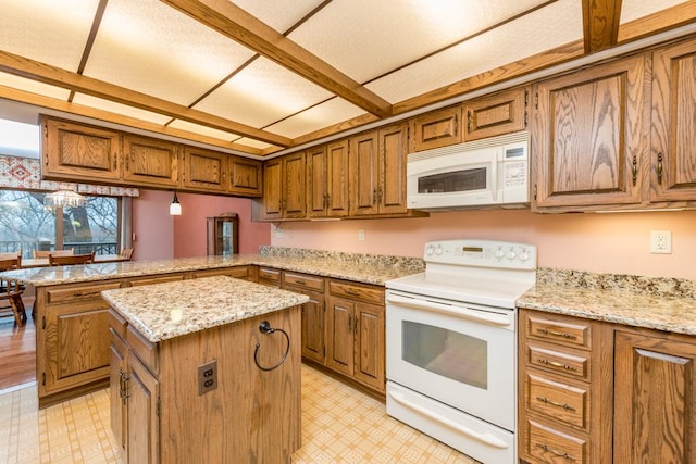 kitchen featuring light stone counters, white appliances, a center island, and kitchen peninsula