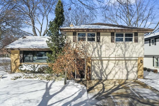 view of front facade with driveway, a garage, and a chimney