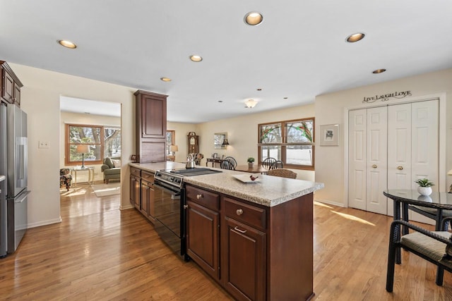 kitchen with range with electric stovetop, light countertops, freestanding refrigerator, light wood-type flooring, and a peninsula