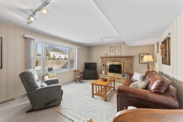 living room featuring a fireplace, rail lighting, and light colored carpet