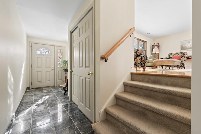 foyer entrance featuring stairs and baseboards