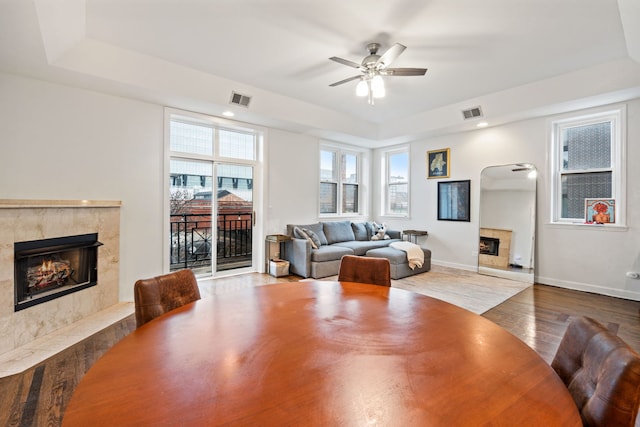 dining space featuring dark wood-type flooring, a fireplace, visible vents, baseboards, and a ceiling fan