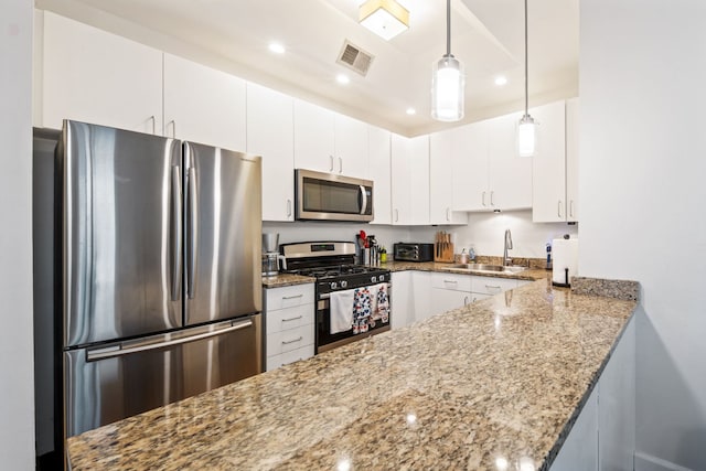 kitchen featuring white cabinets, stainless steel appliances, a sink, and hanging light fixtures