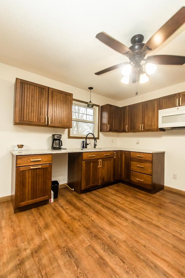 kitchen featuring hanging light fixtures, wood-type flooring, and sink