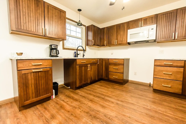 kitchen featuring hanging light fixtures, wood-type flooring, sink, and ceiling fan