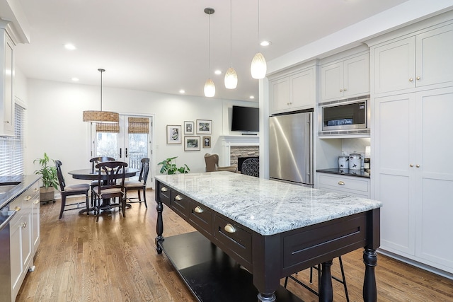 kitchen featuring appliances with stainless steel finishes, wood finished floors, a center island, pendant lighting, and recessed lighting