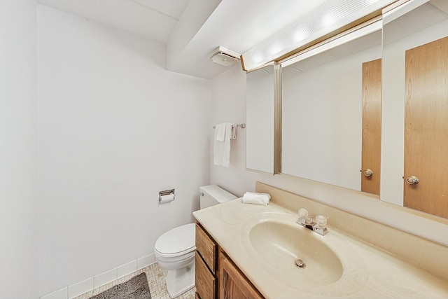 half bathroom featuring vanity, toilet, and baseboards