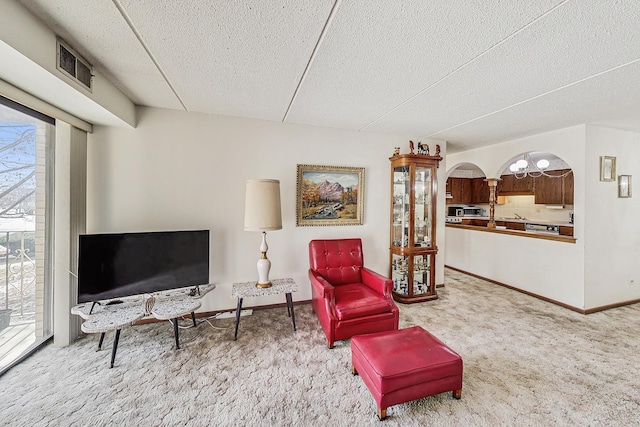 sitting room featuring arched walkways, carpet, visible vents, and baseboards