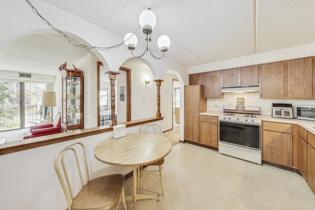 kitchen with a textured ceiling, white gas stove, light countertops, light floors, and stainless steel microwave