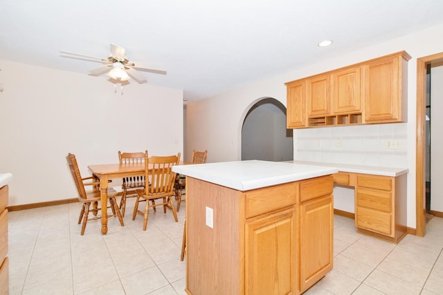 kitchen featuring arched walkways, decorative backsplash, light countertops, light brown cabinetry, and open shelves