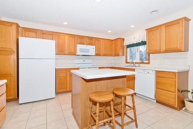 kitchen with light tile patterned floors, light countertops, a kitchen island, a sink, and white appliances