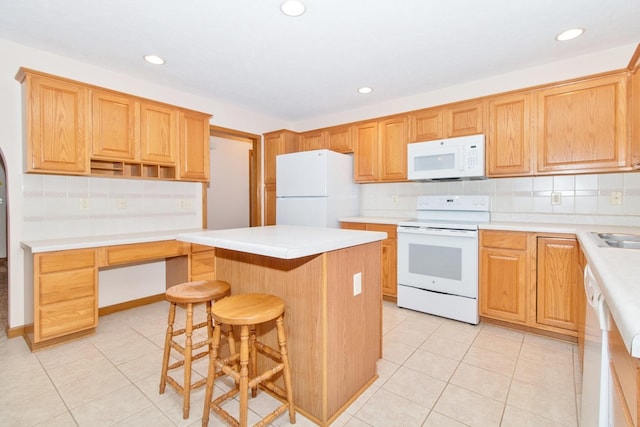 kitchen featuring a breakfast bar, white appliances, a kitchen island, and light tile patterned floors