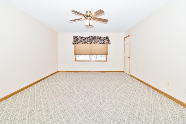 empty room featuring ceiling fan, light colored carpet, and baseboards