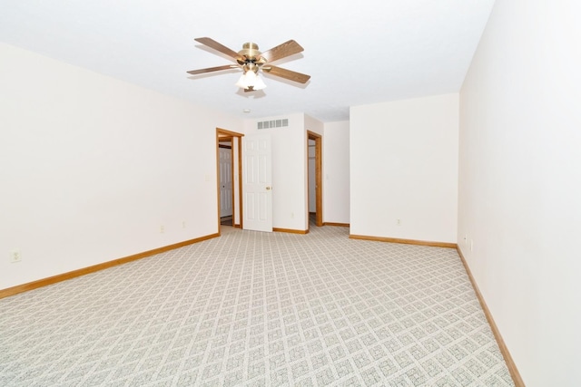 empty room with light colored carpet, visible vents, ceiling fan, and baseboards