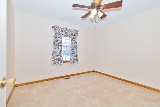 carpeted spare room featuring visible vents, ceiling fan, and baseboards