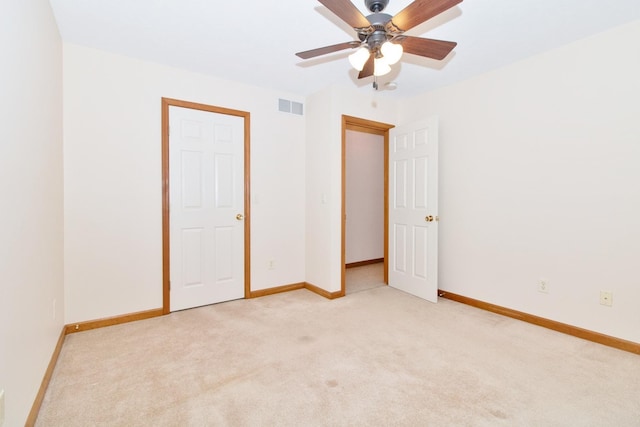 unfurnished bedroom featuring baseboards, a ceiling fan, visible vents, and light colored carpet