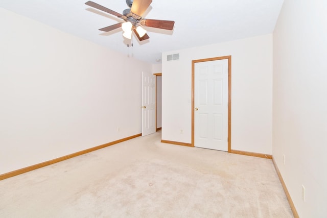 unfurnished room with ceiling fan, light colored carpet, visible vents, and baseboards