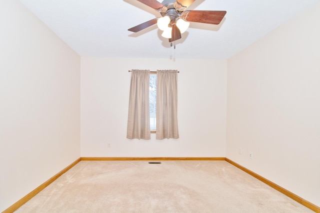 empty room with a ceiling fan, carpet flooring, visible vents, and baseboards