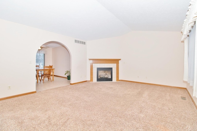 living area featuring lofted ceiling, carpet floors, arched walkways, and visible vents