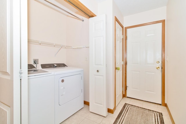 clothes washing area with washing machine and dryer, laundry area, baseboards, and light tile patterned floors