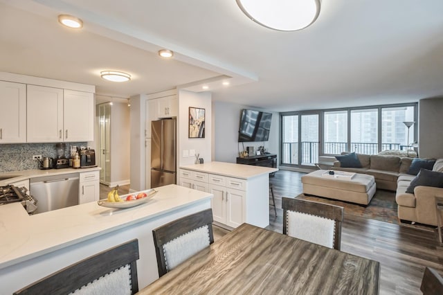 kitchen with backsplash, stainless steel appliances, light stone counters, white cabinets, and dark hardwood / wood-style flooring