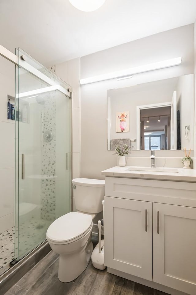 bathroom featuring vanity, hardwood / wood-style floors, an enclosed shower, and toilet