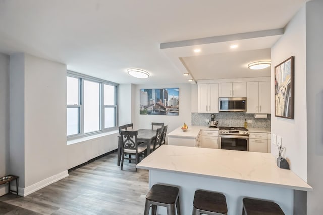 kitchen with stainless steel appliances, a breakfast bar area, white cabinets, and kitchen peninsula