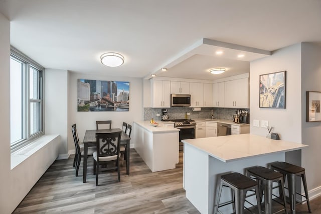 400 E Randolph St Unit 2410, Chicago, IL 60601 - kitchen with appliances with stainless steel finishes, a peninsula, white cabinetry, backsplash, and a breakfast bar area