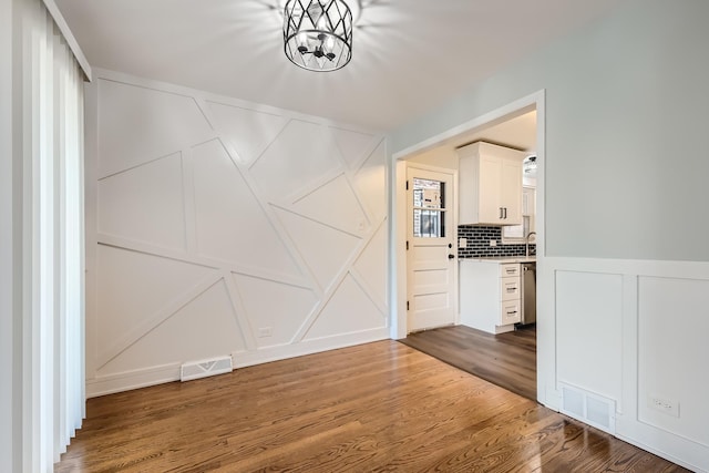 hall with dark wood-type flooring, sink, and a chandelier