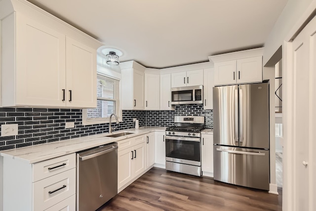 kitchen featuring stainless steel appliances, white cabinetry, light stone countertops, and sink