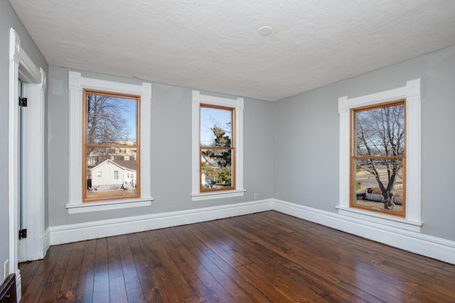 empty room with plenty of natural light, baseboards, and dark wood-style flooring