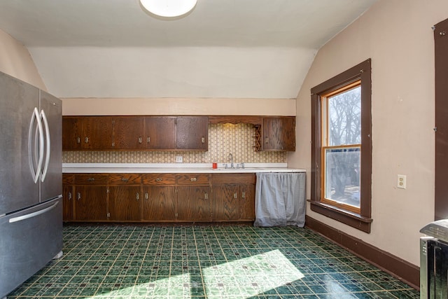 kitchen featuring dark floors, light countertops, freestanding refrigerator, vaulted ceiling, and baseboards