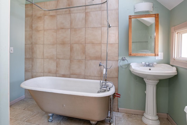 bathroom with baseboards, a soaking tub, a sink, and tile patterned floors