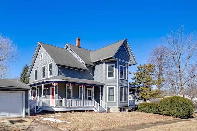 victorian home featuring covered porch, roof with shingles, a chimney, and a garage