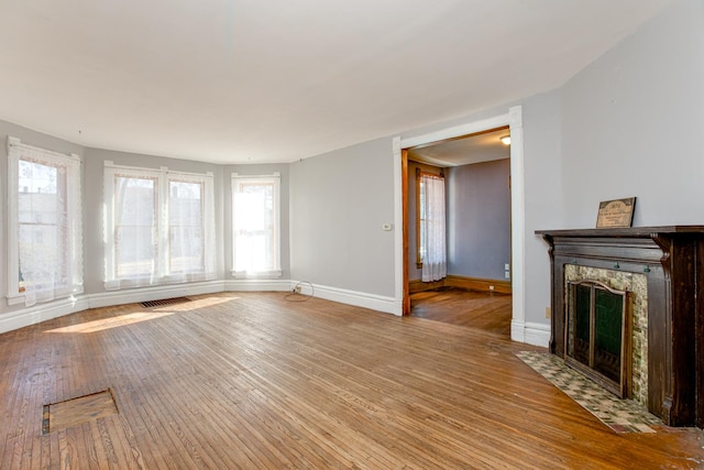 unfurnished living room with plenty of natural light, a fireplace, baseboards, and hardwood / wood-style floors