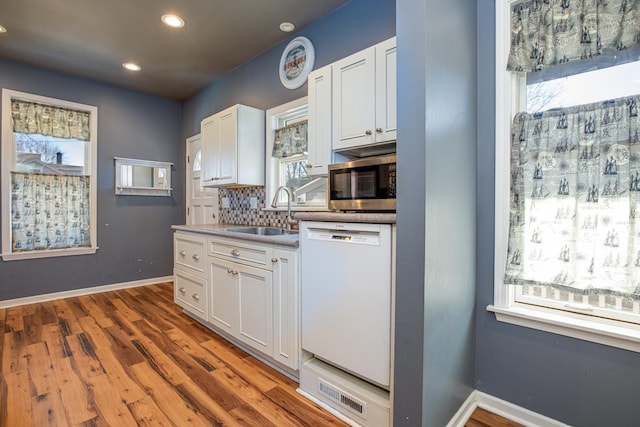 kitchen with white cabinetry, white dishwasher, stainless steel microwave, and a sink