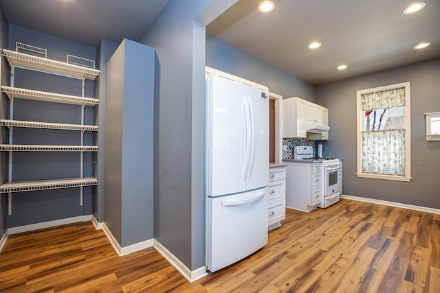 kitchen featuring light wood finished floors, backsplash, white cabinetry, white appliances, and under cabinet range hood