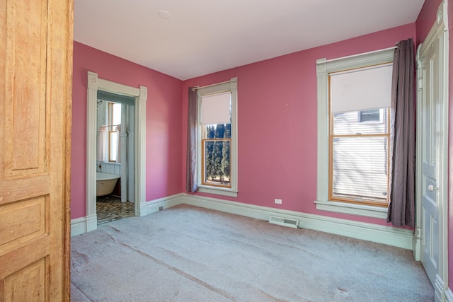 unfurnished room featuring carpet floors, visible vents, and baseboards